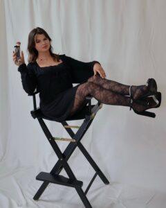 Meet Hayley Dellaria Salons Team | Dellaria Salons Hayley hair and beauty professional on the Dellaria Salons team in Massachusetts holding makeup brushes in a directors chair