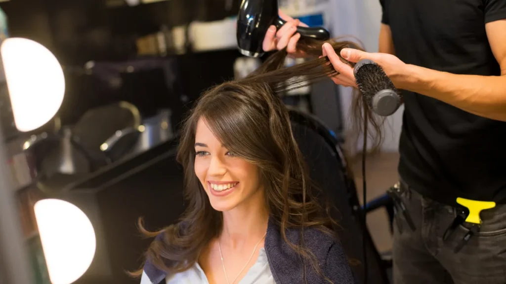 Stylist giving a professional round brush blowout to a smiling client at Dellaria Salons part of the Massachusetts Blowdry Membership